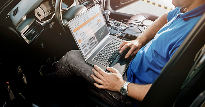 Mechanic man with laptop making car diagnostics at auto service