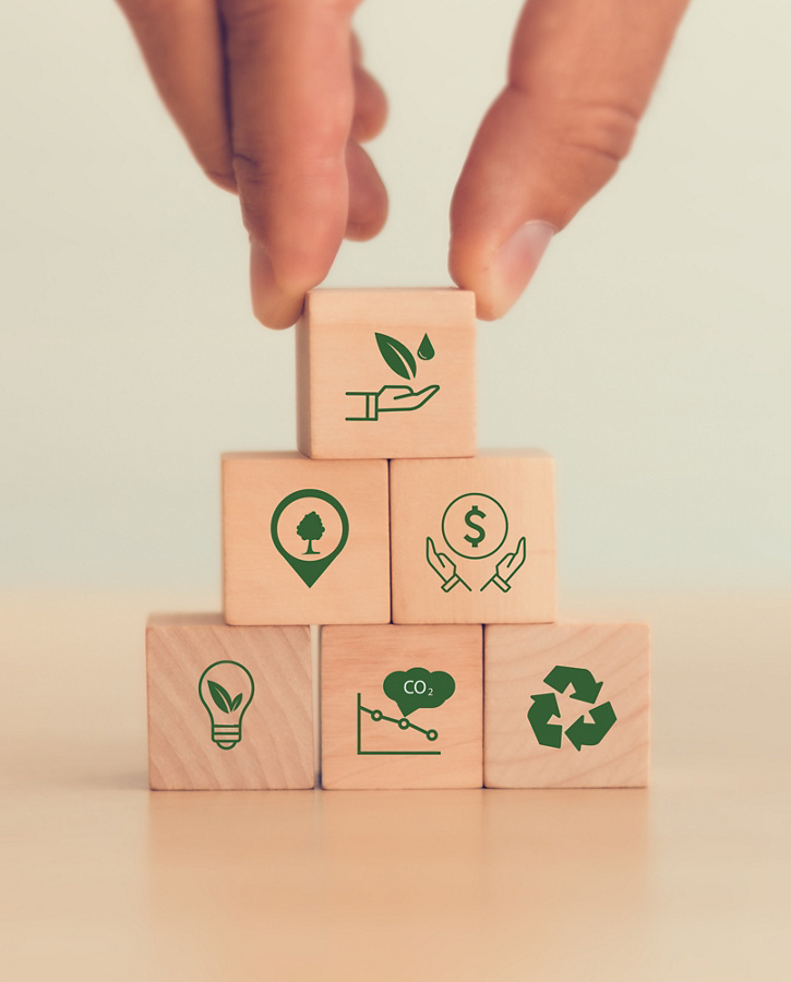 The concept of sustainability or environmental protection. Fingers hold wooden cube with sustainability, environment, green economy, renewable energy, CO2 emission, recycle icon with white background.