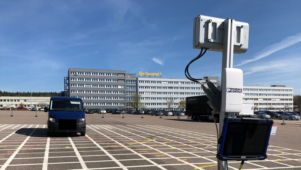 A blue van is parked on a grid-patterned asphalt lot in front of a large building with the "Continental" logo. 