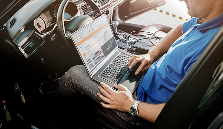 Mechanic man with laptop making car diagnostics at auto service