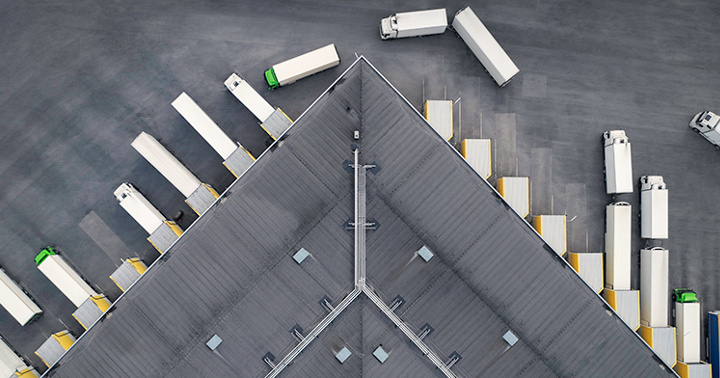 Aerial view of a large distribution warehouse with loading docks and many trucks.